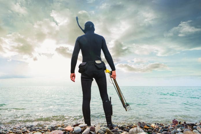 A spearfisher on the beach preparing to dive.