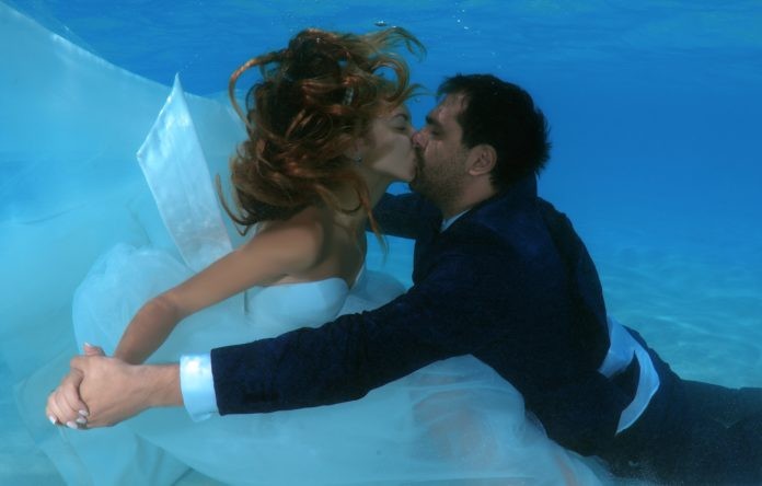 Man and beautiful woman with long hair in a wedding dress kissing under water, Underwater wedding in Indian Ocean, Maldives