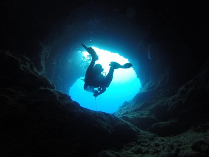 A scuba diver swimming through one of the caverns at Yap Caverns Dive Site.