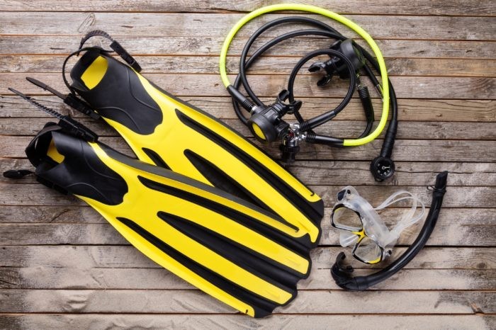 Mask, fins, regulator and snorkel on wooden desk. Equipment for diving