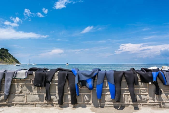 Wetsuits drying on a brick wall with a sea view