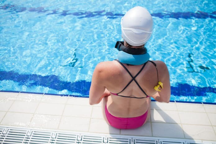 Female freediver preparing for dive at edge of outdoor swimming pool