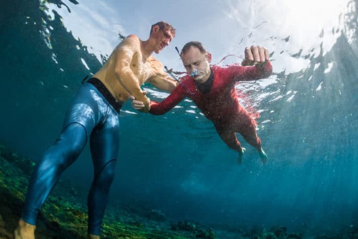 Underwater shot of freediving training for static breath-holds. The buddy is constantly touching the freediver on his back.