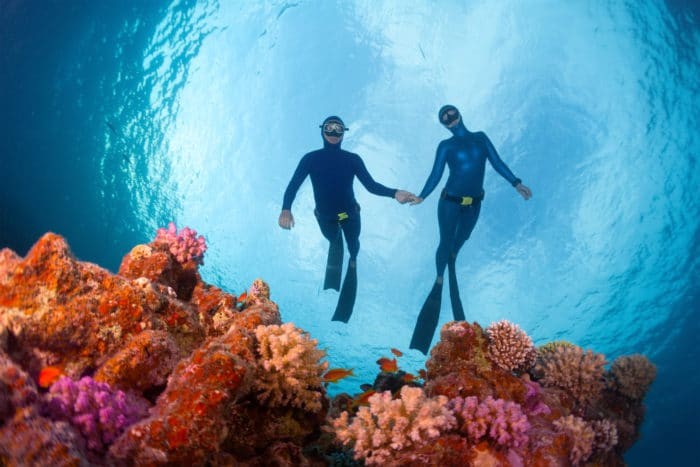 Freedivers gliding over the bright coral reef. Red Sea, Egypt