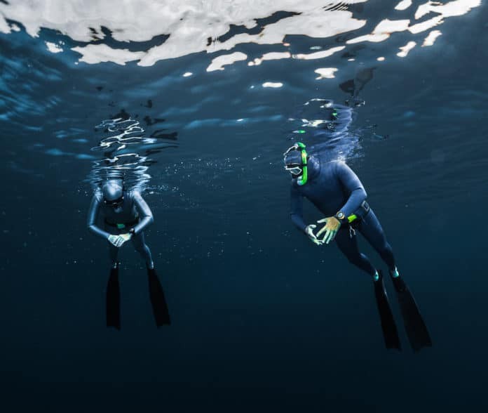 Two free divers preparing for the dive, relaxing on the surface
