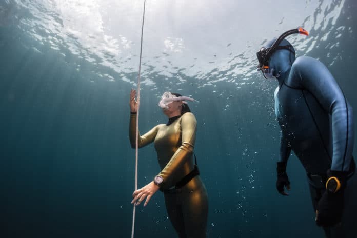 Two female freedivers ascending along the rope in the depth
