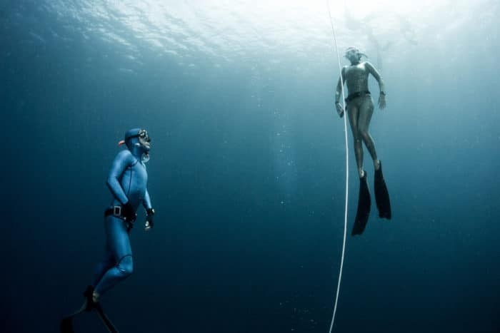 Free diver ascending along the rope in the depth