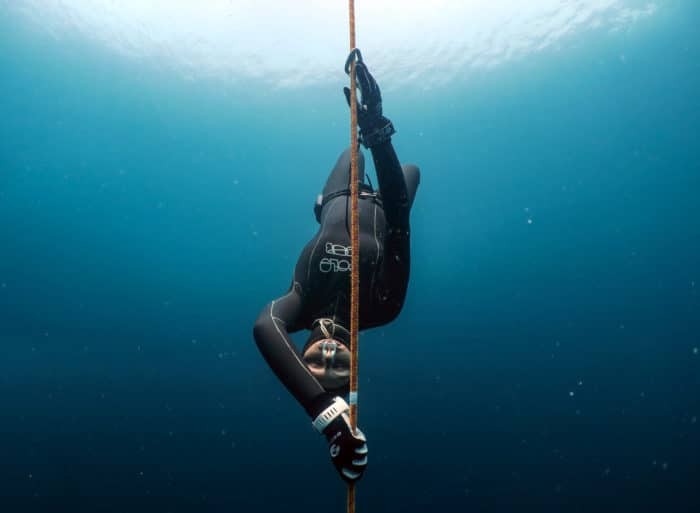 Freediver descending with a dive computer. Photo by <a href="https://www.instagram.com/yahiabarakah/">Yahia Barakah</a>.
