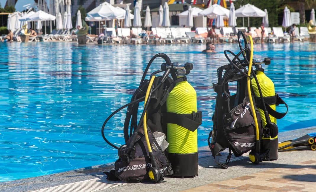 Set of scuba gear set up at the edge of a swimming pool