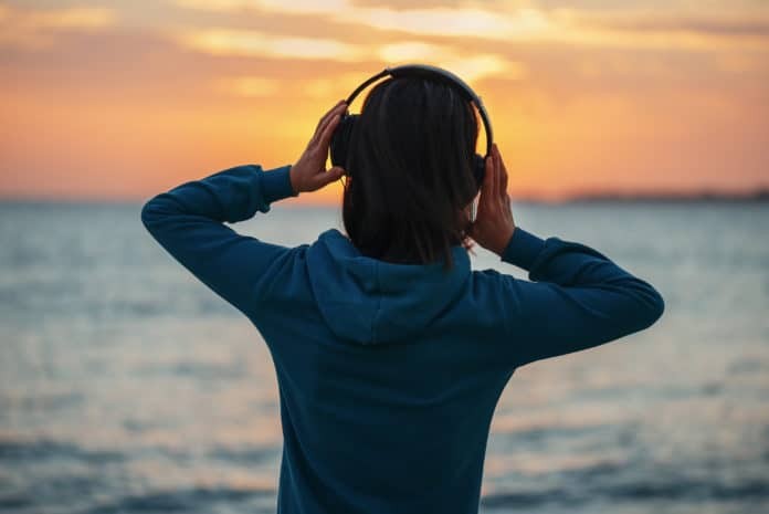 Woman in headphones enjoying sunset over the sea