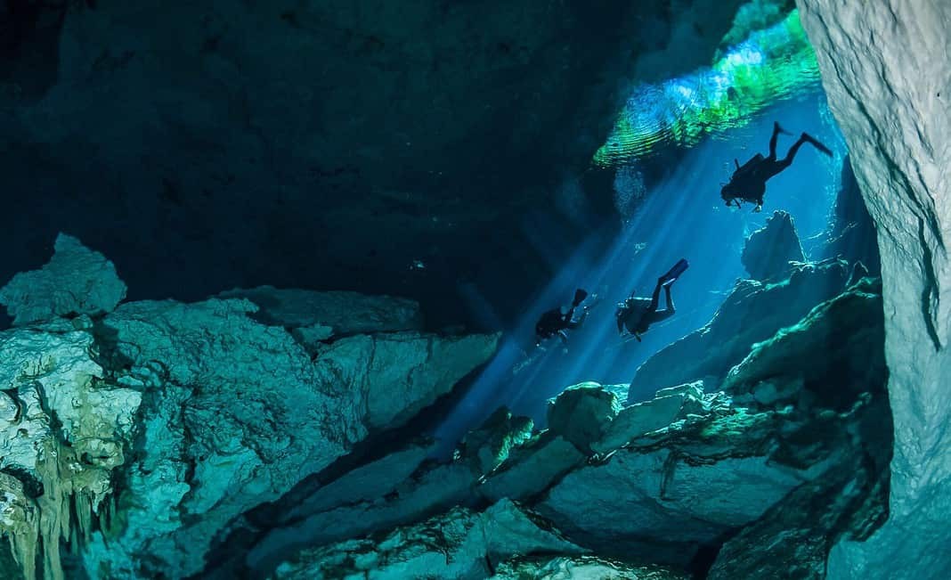 Divers descending into the waters of a cenote on the west coast