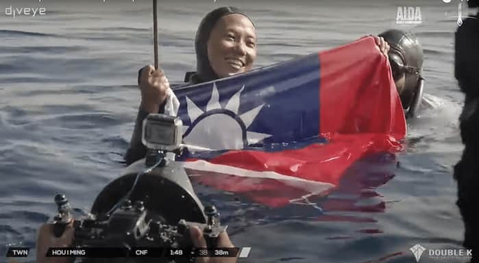 Taiwanese athlete Mia Hou joyfully holds up Taiwan’s national flag after a successful dive to make up for the conspicuously missing national flag that should have been next to her name
