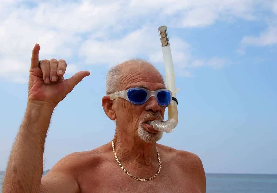 Active senior with dive mask giving friendly shaka wave (Adobe Stock)